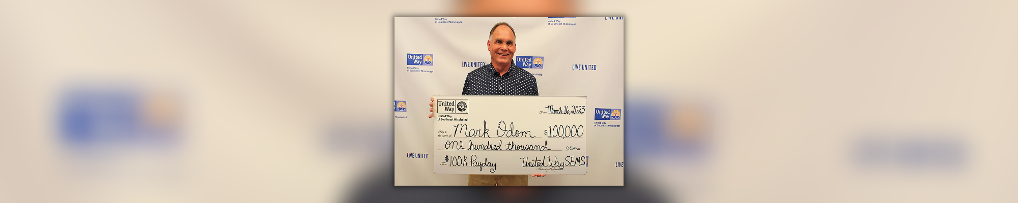 2023 United Way Payday Winner Mark Odom holding a large $100,000 check