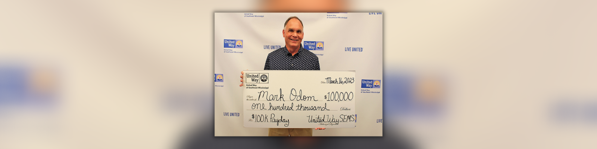 2023 United Way Payday Winner Mark Odom holding a large $100,000 check